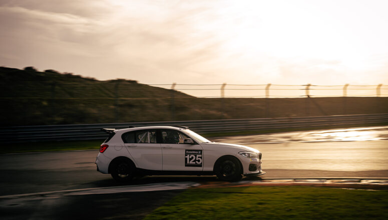 BMW M125i DayVtec BMW M125i DayVtec op Zandvoort tijdens zonsondergang op hoge snelheid.
