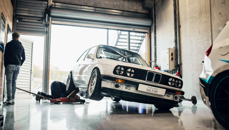 Witte raceauto BMW E30 325i opgekrikt in een pitbox van het circuit van Spa-Francorchamps