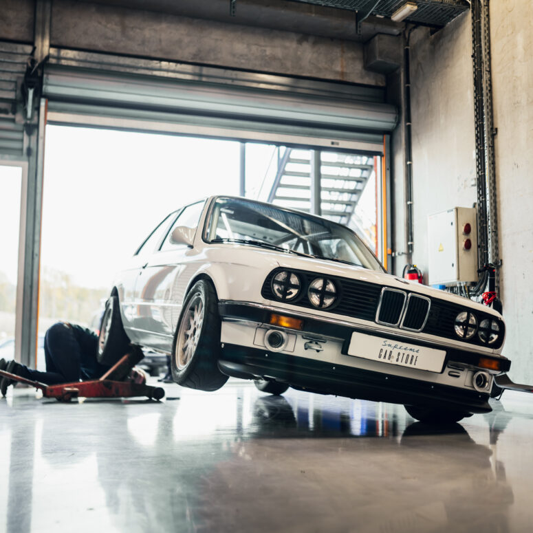 BMW E30 Spa Witte raceauto BMW E30 325i opgekrikt in een pitbox van het circuit van Spa-Francorchamps