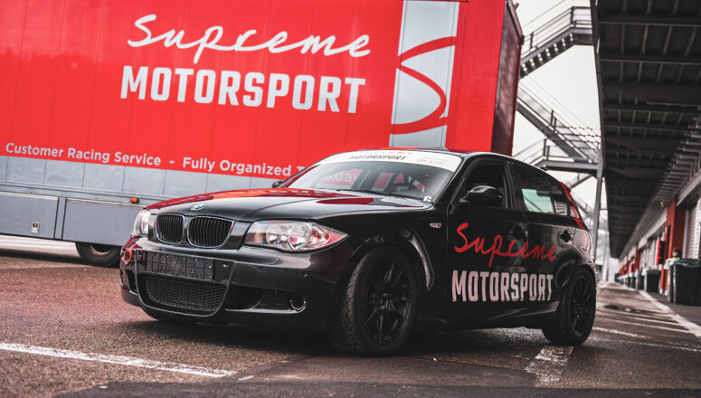 Zwarte BMW 1 serie racer voor een rode trailer van Supreme Motorsport