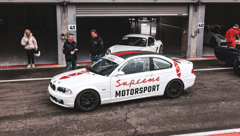 Witte BMW 3 serie raceauto van Supreme Motorsport voor de pitbox op het circuit